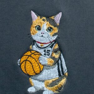 グレーのスウェットに直接刺繍したバスケットボールを持つ三毛猫